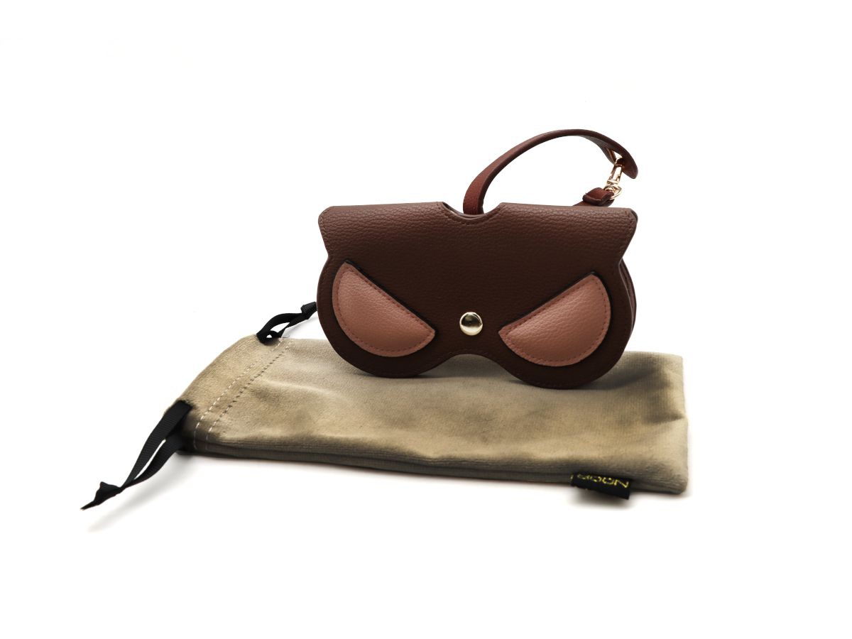 This charming sunglasses case features a playful owl design in warm brown tones with subtle pink accents, combining whimsy with practicality. Its sturdy exterior protects your eyewear from scratches and bumps, while the soft interior lining keeps lenses safe and smudge-free. Compact yet roomy enough for most sunglasses, it’s perfect for everyday use or travel. The combination of cute owl detailing and stylish color makes it both a functional accessory and a fun statement piece.